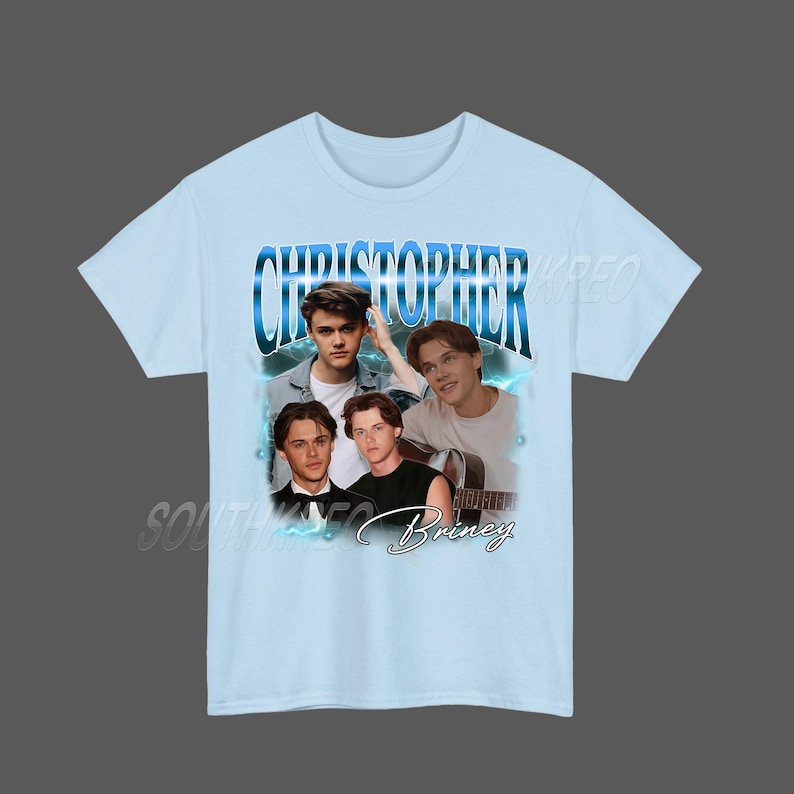 Peut inclure: T-shirt bleu clair avec un collage de quatre images d'une personne. Le nom "CHRISTOPHER" est &eacute;crit en bleu, dans une police stylis&eacute;e en haut. Le nom "Briney" est &eacute;crit en cursive en bas.
