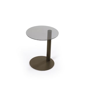 Op de afbeelding: Een bijzettafel met een rond, halfdoorzichtig grijs glazen blad, ondersteund door een enkele, dikke, cilindrische kolom van donkerbruin metaal die verbonden is met een platte, ronde voet van donkerbruin metaal voor een gebalanceerd meubel.