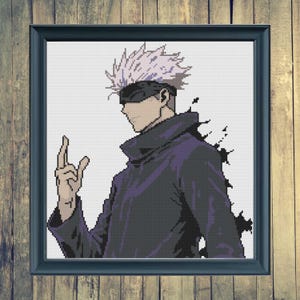 May include: Framed cross-stitch art featuring a character with spiky white hair, a black blindfold, and a dark purple outfit. The artwork is set against a white background and framed in a dark blue frame. The character is making a hand gesture.