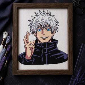 May include: A cross-stitch embroidery of an anime character with spiky white hair, bright blue eyes, and a dark high-collared jacket. The character is making a hand gesture with two fingers raised. The piece is displayed in a dark wooden frame.