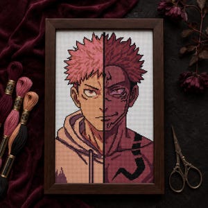 May include: A framed cross-stitch portrait featuring a split-face character design. The left side shows a person with spiky pink hair and a light hoodie, while the right side depicts a dark, demonic version with purple skin and black markings.