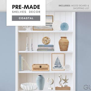 May include: A white coastal-themed bookshelf filled with decorative items. Includes a framed sailboat print, a woven box, a ceramic vase, and a variety of other coastal decor. The text "PRE-MADE SHELVES DECOR COASTAL" is visible.