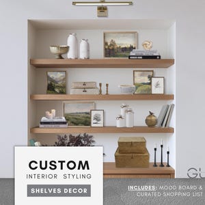 Puede incluir: Una estantería de madera empotrada con varios objetos decorativos. Las estanterías exhiben arte paisajístico enmarcados, jarrones blancos, libros y cajas decorativas. La imagen incluye el texto "CUSTOM INTERIOR STYLING SHELVES DECOR".