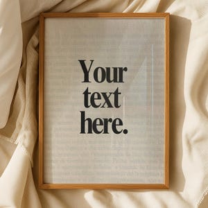 Peut inclure: Un cadre en bois clair contenant une impression avec le texte "Your text here" en noir. L'arrière-plan semble être une page de livre. Le cadre est rectangulaire et l'impression est centrée.
