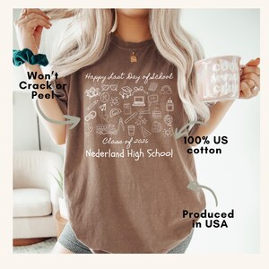 May include: Brown t-shirt with the text "Happy Last Day of School" and a collection of school-related doodles. The shirt also features the text "Class of 2026 Nederland High School" and is made of 100% US cotton.