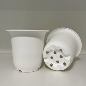 May include: Two white plastic plant pots. One pot has drainage holes in the bottom.