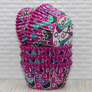 May include: A stack of pink and white cupcake liners with a geometric pattern. The liners feature a black and white abstract design with teal and purple accents.