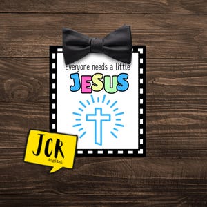 May include: A black and white printable sign with a black bow tie on top. The sign says "Everyone needs a little JESUS" in colorful letters with a blue cross and a sunburst behind it. The sign also has a JCR digital logo in the bottom left corner.