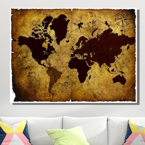 Könnte beinhalten: Ein gerahmter Weltkarten-Druck mit einem Vintage-Look. Die Karte hat ein braunes und goldenes Farbschema mit einer Windrose in der oberen rechten Ecke. Die Karte wird über einem weißen Sofa mit bunten Kissen angezeigt.