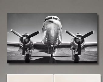 May include: A black and white photograph of a vintage airplane with propellers. The airplane is on a runway with a blurred background.