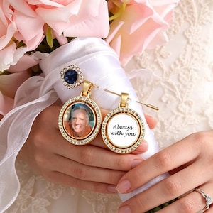 May include: A wedding bouquet of pink and white roses, held by a person in a white lace wedding dress. Two gold pendants with photos and the text "Always with you" are attached to the bouquet.