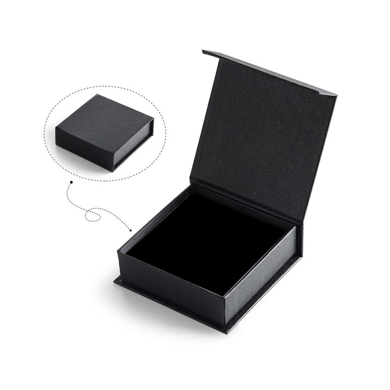 May include: A black square box with a lid that is open. The box is made of a textured material and has a black interior.