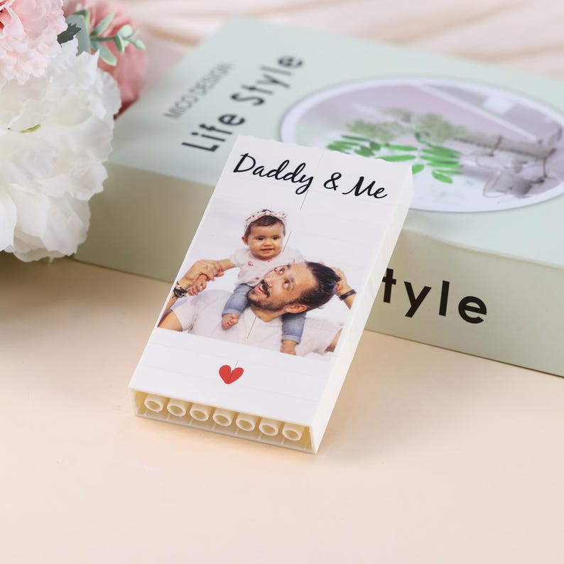 Puede incluir: Un bloque blanco con una foto de padre e hijo, con el texto "Daddy & Me" y un coraz&oacute;n rojo. El bloque est&aacute; sobre una caja verde claro con las palabras "Life Style".