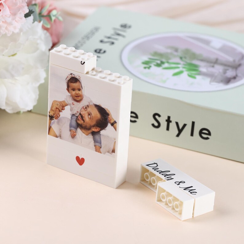 Puede incluir: Un bloque blanco estilo Lego con una foto de un padre y un ni&ntilde;o, un coraz&oacute;n rojo y el texto "Daddy & Me". Es un regalo personalizado, posiblemente un marco de fotos o un objeto decorativo.