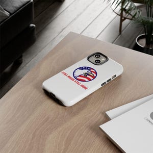 May include: White phone case with a bald eagle and American flag design. The text "Still MAGA Still Here" is printed on the case.