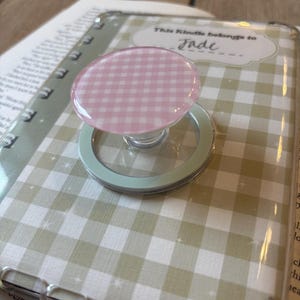 May include: A clear phone case with a light green and white gingham pattern. A pink and white gingham PopSocket is attached.