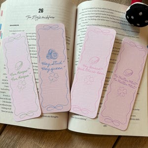 May include: Four pink paper bookmarks with decorative edges and text. The bookmarks feature a football and clover design. Text includes "For Keeps", "Hey, Stud, Hey, queen", "Hey Gerard, Yeah Claire Bear", and "No Matter What".