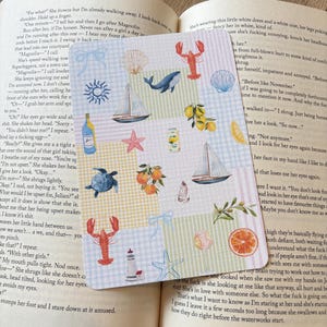 May include: A sticker sheet with a patchwork design, featuring nautical and beach-themed illustrations. Includes sailboats, seashells, a whale, lobster, starfish, and citrus fruits. The sheet is designed with a coastal theme.