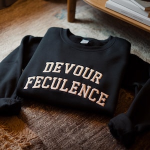 May include: Black sweatshirt with the text "DEVOUR FECULENCE" in a cream color.