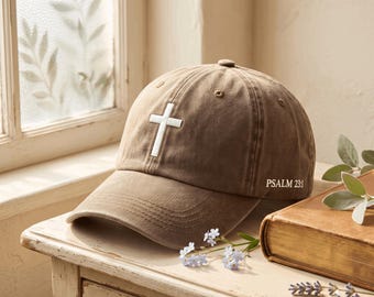 以下が含まれることがあります： フロントパネルに白い刺繍の十字架、サイドに白い刺繍でPSALM 23:1の文字が施された茶色の野球帽。この帽子には、カーブしたつば、上部のボタン、通気用のステッチ入りアイレットが付いています。
