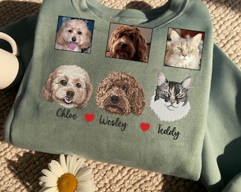 May include: Sage green sweatshirt featuring embroidered portraits of three pets: two dogs and a cat. The names "Chloe", "Wesley", and "Teddy" are embroidered below the pet portraits, with a red heart symbol between each name.