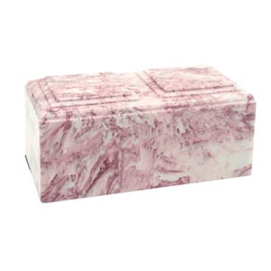 May include: A pink and white marble cremation urn with a rectangular shape.