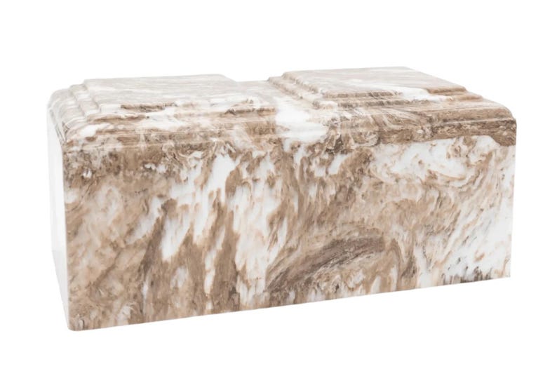 May include: A white and brown marble cremation urn with a rectangular shape.