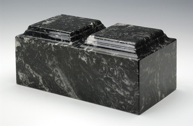 May include: A black and white marble cremation urn with a double-tiered design. The urn has a smooth, polished finish.