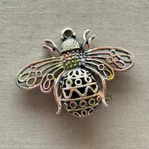 May include: A silver bee charm with a detailed, intricate design. The bee has a black and white patterned body with pink, orange, and green accents.