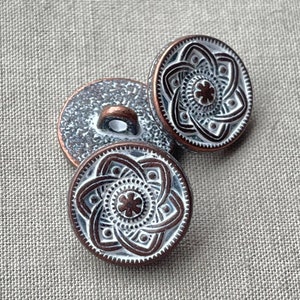 May include: Three silver and copper buttons with a decorative, intricate design. The buttons have a raised, circular pattern with a smaller circle in the center.