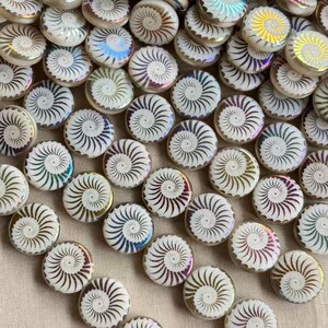 May include: A collection of round, flat buttons featuring a white base with a dark brown spiral pattern radiating from the center. Each button has an iridescent, pearlescent finish that reflects light, creating a subtle rainbow sheen.