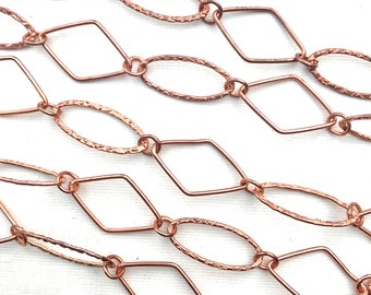 May include: Close-up of a copper-colored chain with alternating diamond and oval links. The oval links have a textured, hammered appearance. The chain is displayed against a white background, highlighting the intricate design and warm tones.