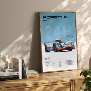 K&ouml;nnte beinhalten: Ein blaues und oranges Poster eines Porsche 917 Rennwagens mit dem Text "PORSCHE 917 24H 1970" und technischen Daten.