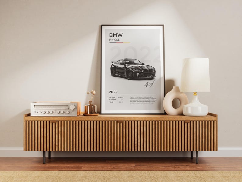 May include: A black and white poster with a black BMW M4 CSL car on a white background. The poster has the text "BMW M4 CSL 2022" and a signature at the bottom.