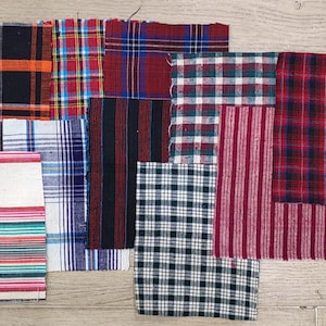 Könnte beinhalten: Eine Sammlung von Stoffmustern in verschiedenen Karomustern und Streifenmustern. Die Muster zeigen eine Reihe von Farben, darunter Rot, Schwarz, Blau, Grün und Weiß. Die Stoffe scheinen aus Baumwolle oder einem ähnlichen Material zu bestehen, das sich für Quilt- oder Bastelprojekte eignet.
