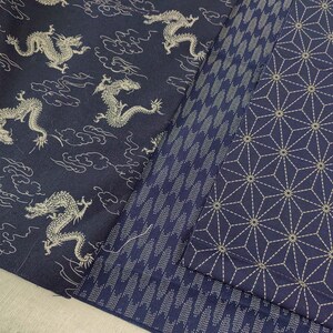 May include: Three different fabric swatches in a dark blue color with white patterns. The first swatch has a repeating pattern of dragons and clouds. The second swatch has a repeating pattern of small white dots. The third swatch has a repeating pattern of geometric shapes.