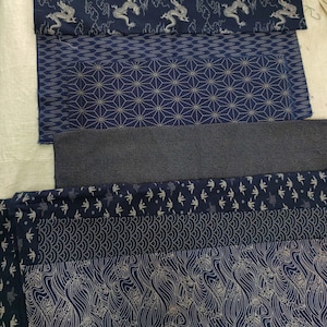 May include: Five different fabric swatches in shades of blue with white patterns. The patterns include a geometric design, a wave pattern, a bird pattern, and a dragon pattern.