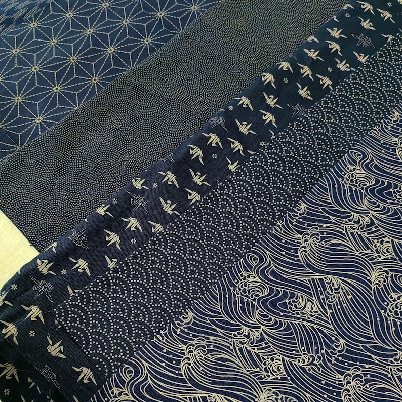 May include: Five different fabric swatches with a dark blue background and a gold pattern. The patterns include geometric shapes, origami cranes, dots, and waves.