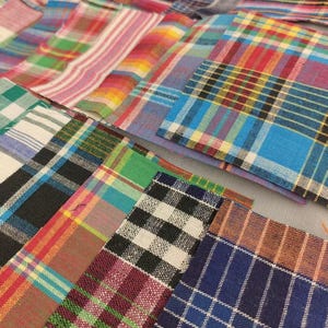 Könnte beinhalten: Eine Sammlung farbenfroher Stoffquadrate mit Karomuster in verschiedenen Mustern und Farbtönen. Die Quadrate weisen eine Mischung aus leuchtenden Farben auf, darunter Rot, Blau, Grün und Gelb, die in einer ansprechenden Anordnung angeordnet sind.