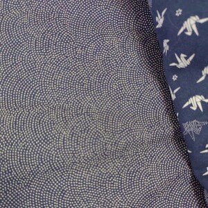 May include: A close-up of a dark blue fabric with a white pattern of small dots arranged in a wave-like design. The fabric is textured and has a subtle sheen.