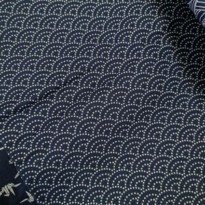 May include: A close-up of a dark blue fabric with a white pattern of small circles arranged in a wave-like design.
