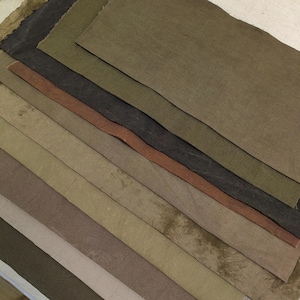 Puede incluir: Un conjunto de ocho muestras de tela en varios tonos de verde, marrón y beige. Las muestras están dispuestas en un degradado de color, con el verde más oscuro en la parte superior y el beige más claro en la parte inferior.