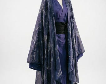 May include: A dark blue kimono-style robe with a silver pattern, worn over a matching blue outfit. The robe features wide sleeves and is cinched with a black belt. The outfit is displayed on a mannequin against a white backdrop.