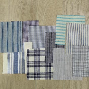 Pode incluir: Conjunto de amostras de tecido em vários padrões e cores, incluindo azul, branco e preto. As amostras estão dispostas em uma grade sobre uma superfície de madeira.