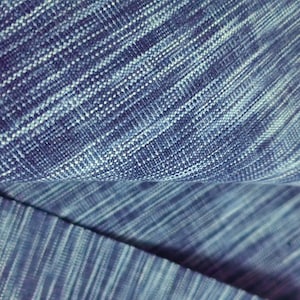 May include: Close-up of a blue and white textured fabric with a subtle striped pattern.
