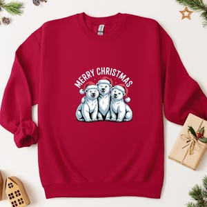 May include: A red sweatshirt with a graphic of three white polar bears wearing Santa hats, and the text "MERRY CHRISTMAS". A festive holiday design.