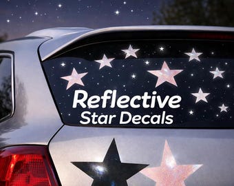 May include: Silver car with reflective star decals on the rear window. The decals include various sizes of stars, some with a galaxy design and others with a glittery pink appearance. The text "Reflective Star Decals" is displayed in white.