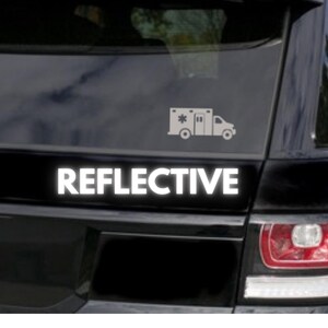 May include: A black car with a white reflective sticker that says "REFLECTIVE" and a white silhouette of an ambulance with a star on the side.