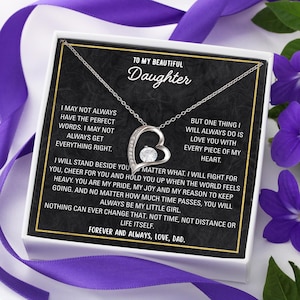 May include: A silver-toned heart-shaped pendant necklace with a clear gemstone center, presented in a white box with a black interior. The box features text that reads "To My Beautiful Daughter" and a heartfelt message from "Dad."