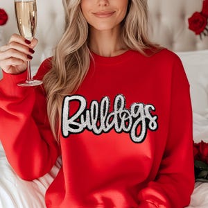 May include: Red sweatshirt with a white and black "Bulldogs" graphic on the front.